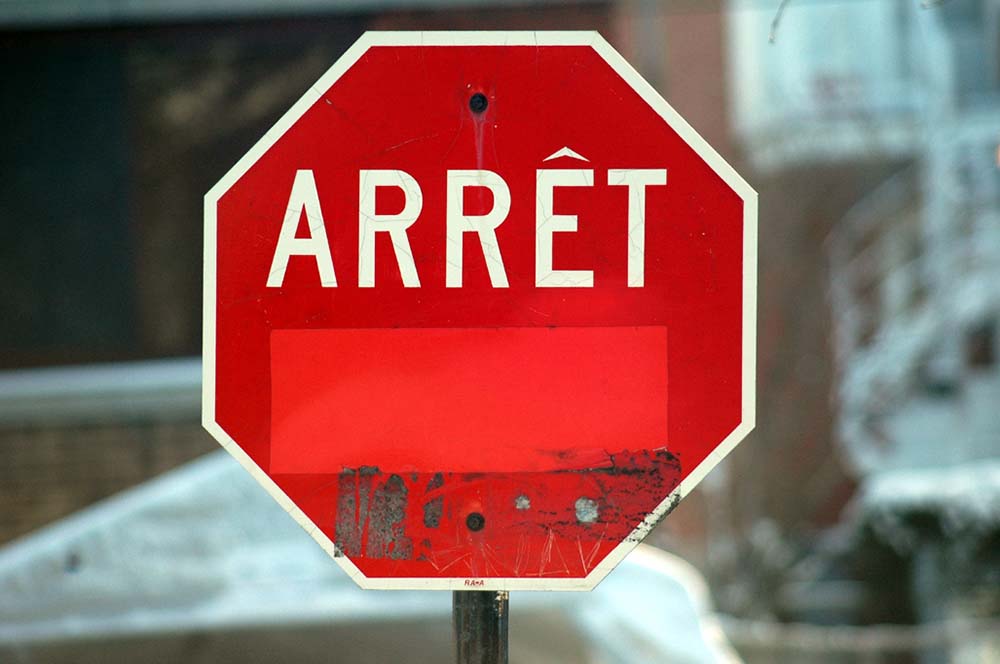 Stop sign with English-language “Stop” covered, 2006. Photograph by Caribb.