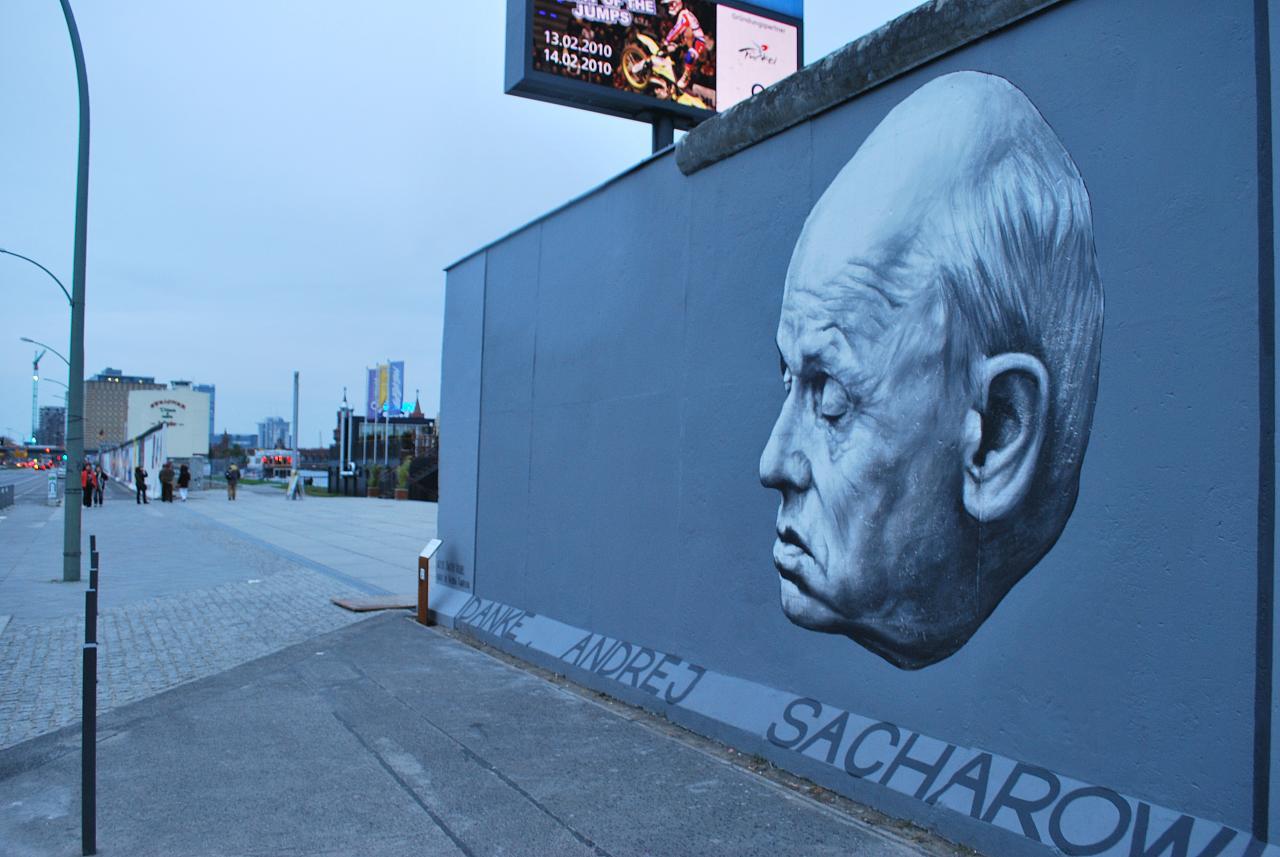 A segment of the Berlin Wall painted with a blue mural featuring the face of a man and the words Thank you Andrey Shakharov, in Germa