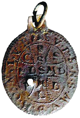 A circular metal amulet embossed with a cross and letters