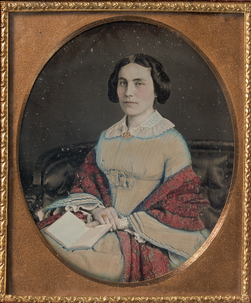 Seated young woman wearing a shawl, holding an open book in her lap, American, c. 1850.