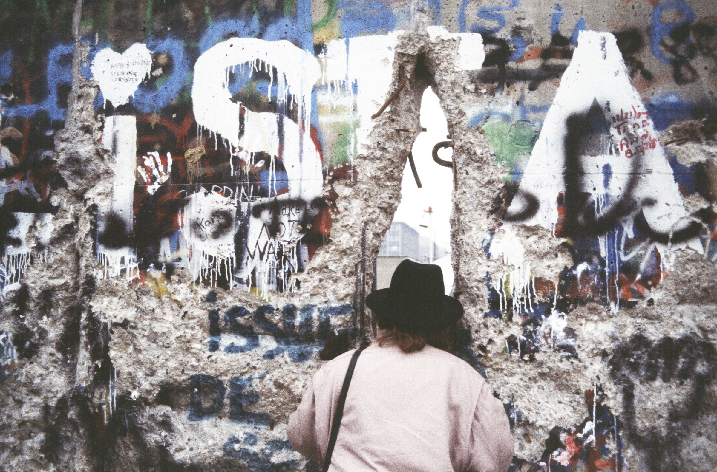 A woman looks through a hole in the Berlin Wall.