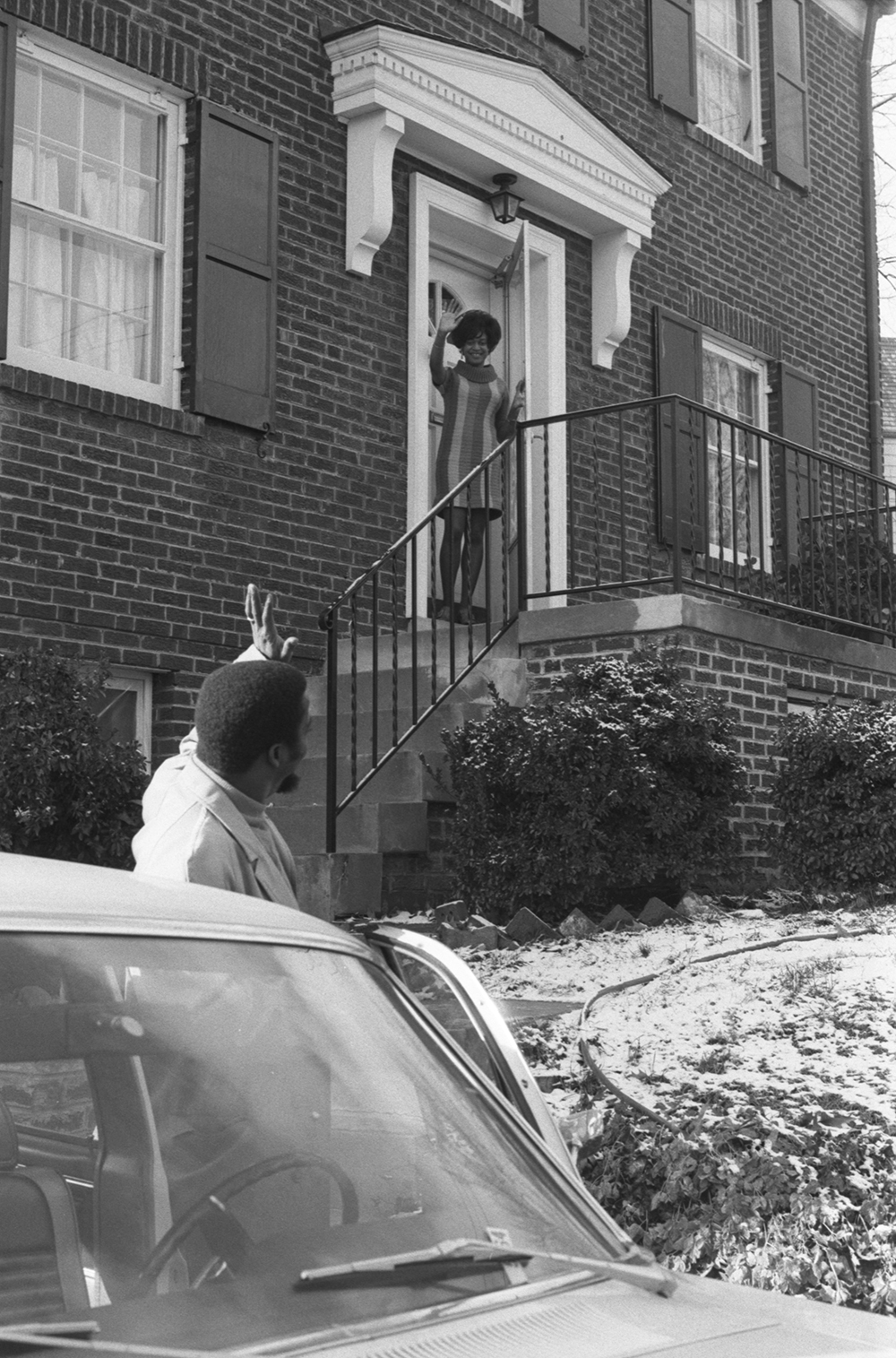 Man at his car, waving goodbye to a family member in the doorway of a house in the suburbs, 1969. Photograph by Roland L. Freeman. Library of Congress, Prints and Photographs Division.