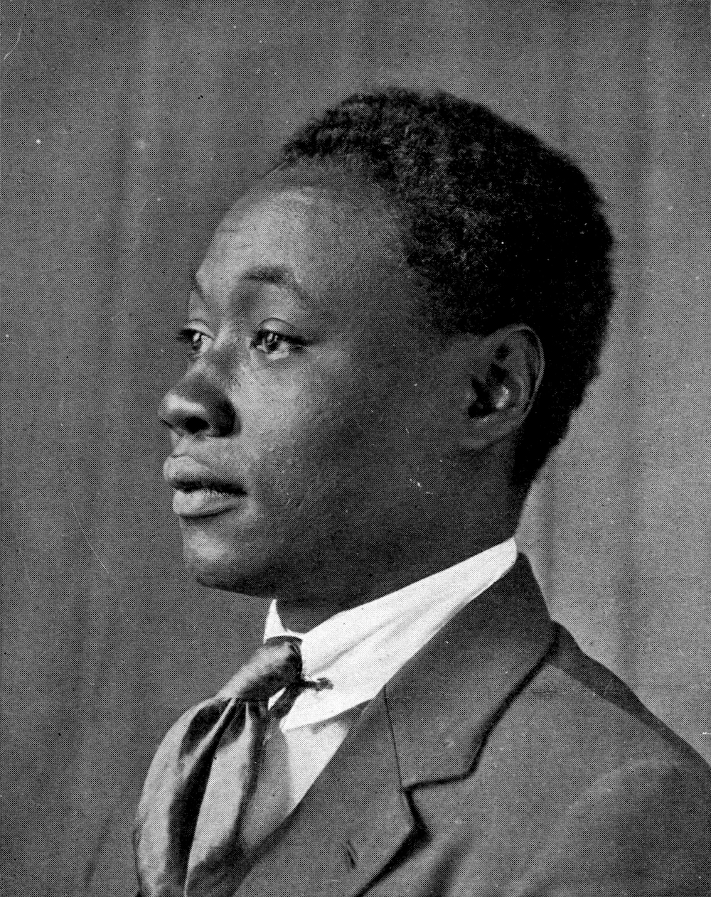 A photograph of a young Claude McKay in 1920. He is in profile, wearing a suit and tie.