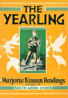 Book cover for The Yearling. A yellow background with black text. A green rectangle in the center of the cover shows a drawing of a young boy holding a fawn, a farm house, and trees in the distant background.