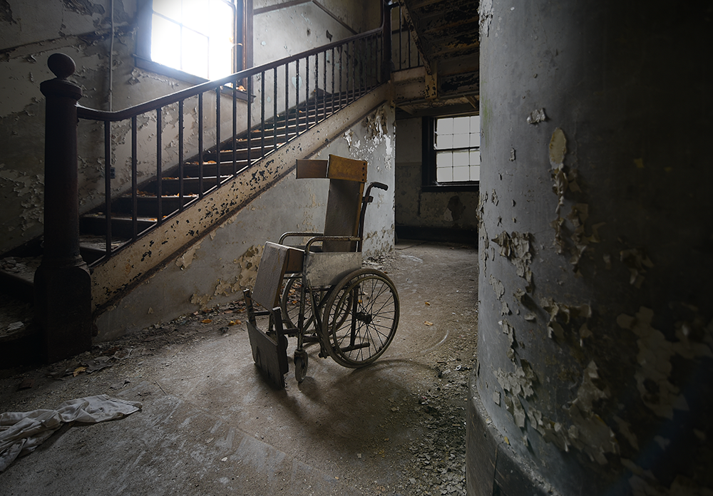 A wheelchair sits at the foot of the stairs in the Fernald’s West Building, 2016. The oldest building constructed at the site, it opened in 1890. Photograph by David Whitemyer.