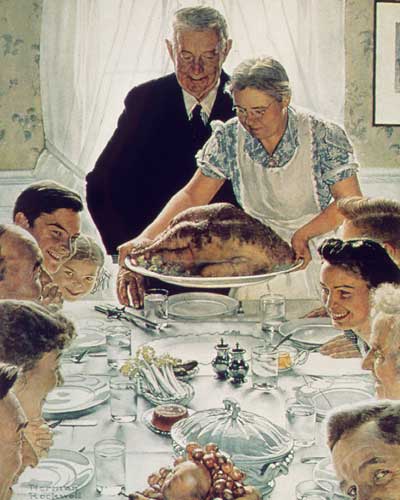 A gray-haired man and woman placing a turkey on a table before several children