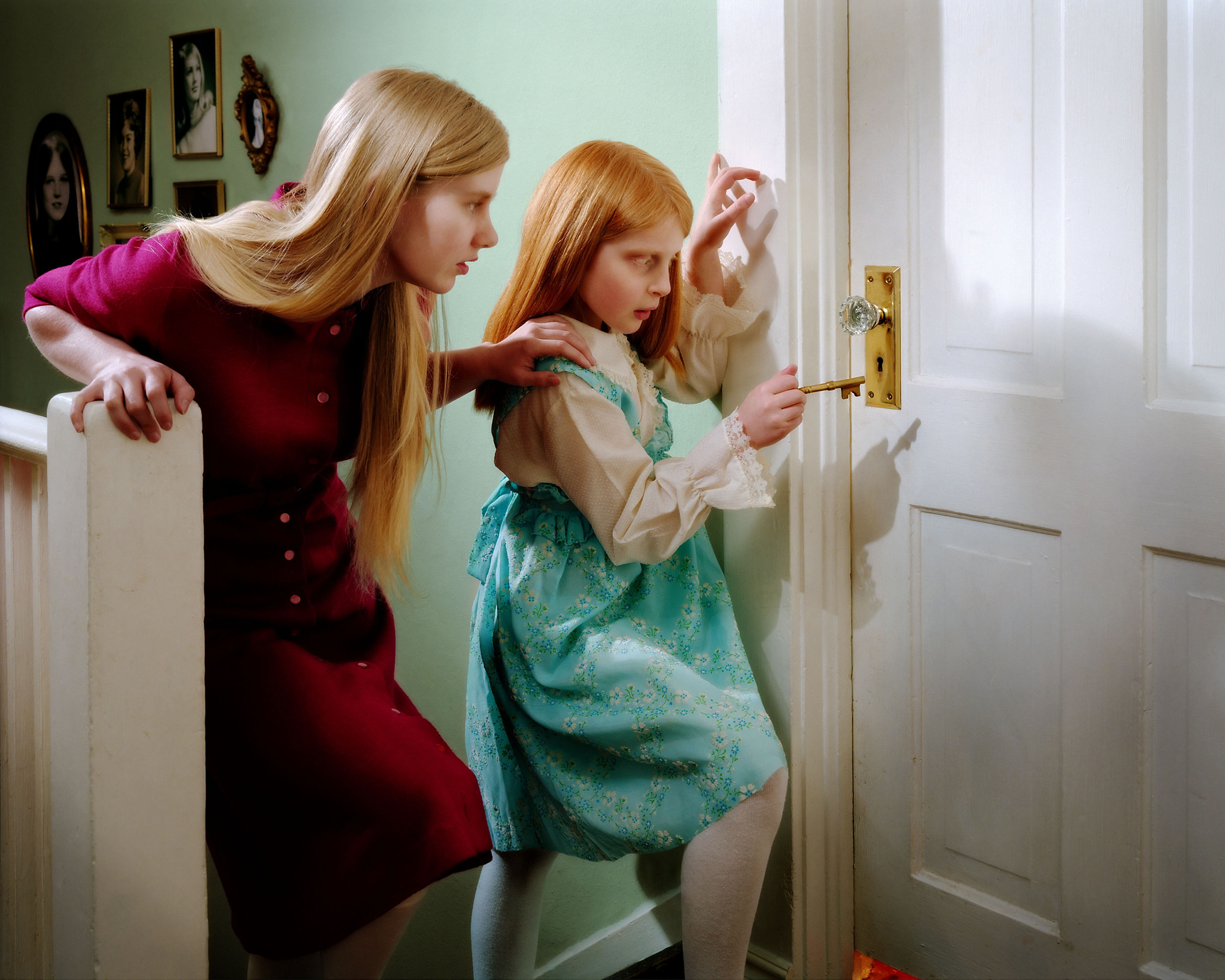 Color photograph of two young girls holding a key up to a locked door.