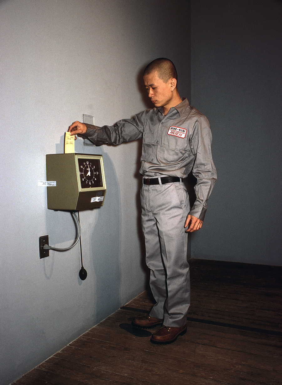 Color photograph of a man punching a time clock.