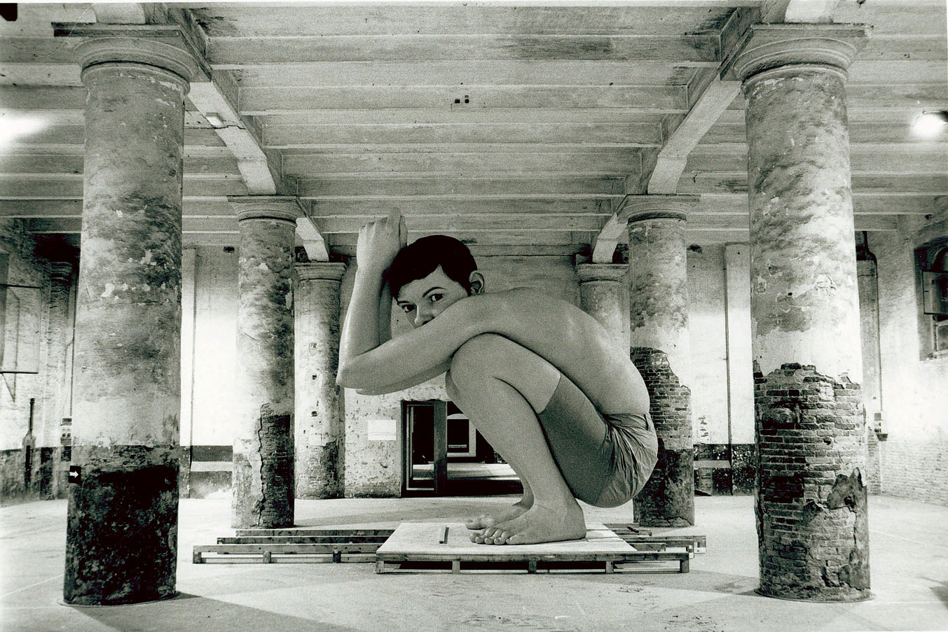 Photograph of a massive realistic sculpture of a young boy crouching down.