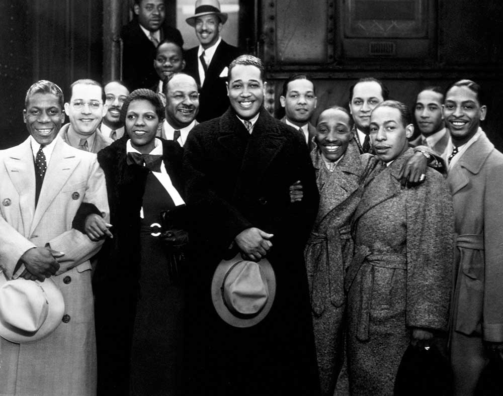 Duke Ellington and his band posing in front of a train, Los Angeles, 1934.