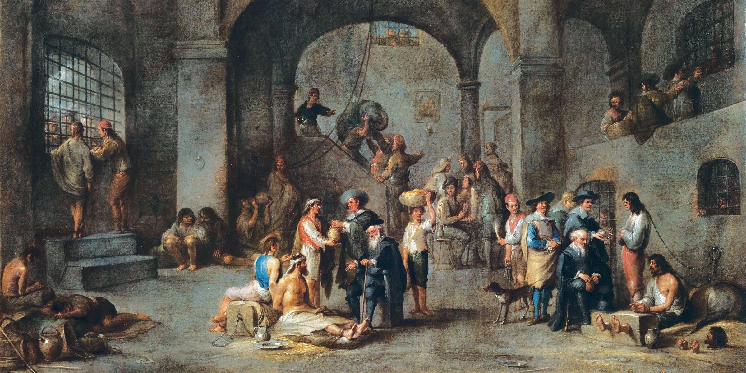 Group of men, including a man handing another a jug, inside a stone prison.