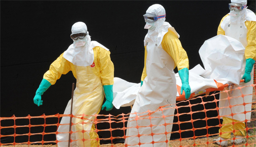 Color photograph of aid workers in hazmat suits carrying an ebola victim.
