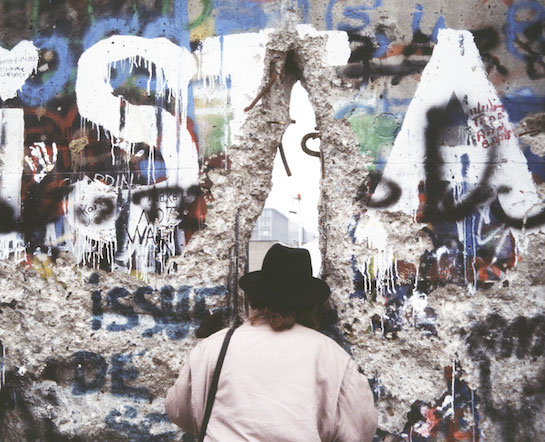 A woman looks through a hole in the Berlin Wall.