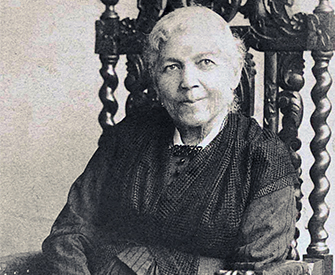 A photograph of Harriet Jacobs, seated in a chair, smiling