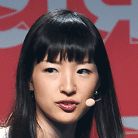 Headshot of a young woman with black bangs and a lavalier microphone