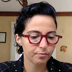 Short-haired woman with red glasses looking down