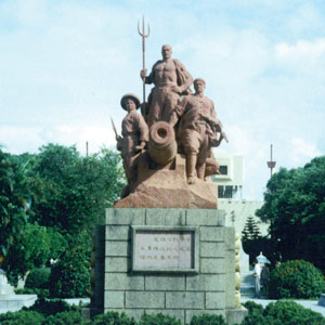 a photograph of a monument depicting three men standing over a cannon. One holds a trident.