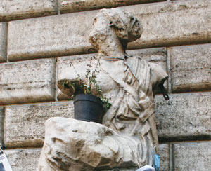 An ancient statue of a seated person with a small vessel on their lap.