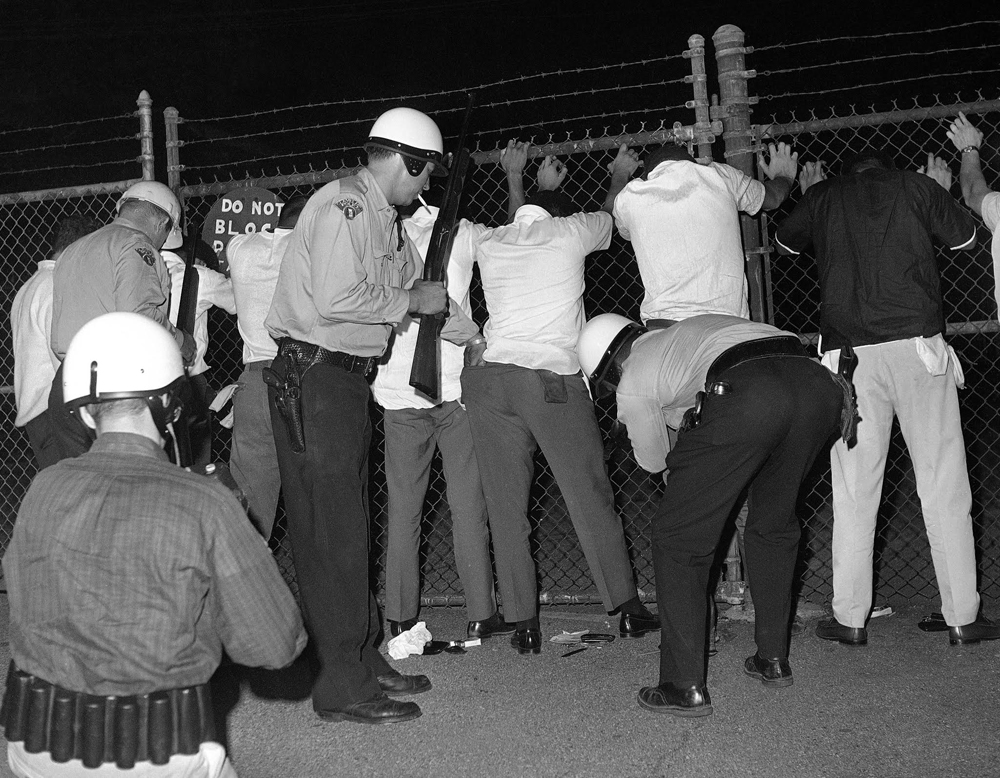 Police search youths in riot area of Cleveland, July 23, 1966 as trouble continued for a fifth night with reports of shooting and minor incidents, AP Photo/Charles Knoblock.