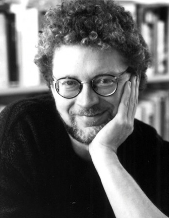 Black and white photograph of Sven Birkerts sitting in front of a bookshelf.