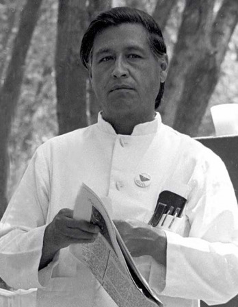 Black and white photograph of a dark-haired man in a white shirt holding a newspaper