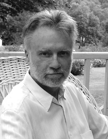 Black and white photograph of John Crowley sitting on a porch.