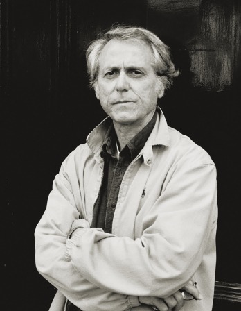 Don DeLillo standing outside in a jacket, black and white photo