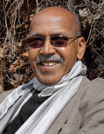 Smiling man with a mustache wearing sunglasses and a scarf