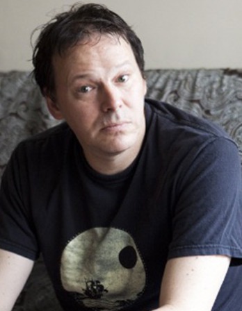 Color photograph of author David Graeber wearing a t-shirt.