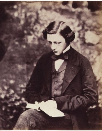 Sepia toned photograph of Lewis Carroll in a suit, reading a book