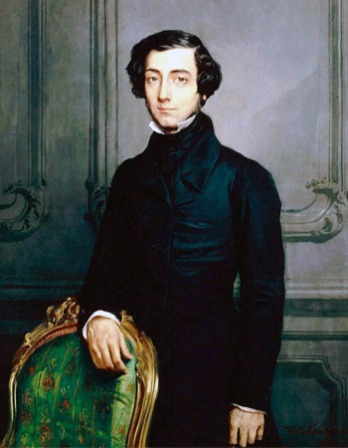 Portrait of Alexis de Tocqueville wearing a black suit and standing in front of a chair.