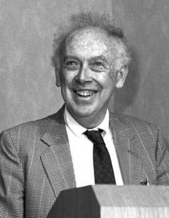 Smiling man with thin hair sticking out at a podium