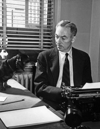 Black and white photograph of E. B. White sitting at his typewriter with his dachshund.