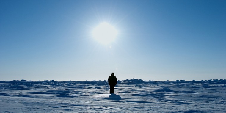 Photograph of a man standing on snow.