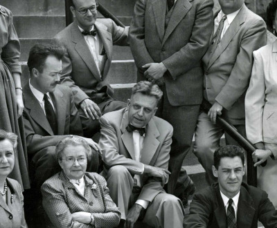 Black and white photograph of men and women seated on stone steps.