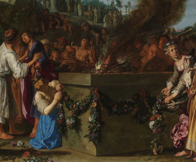Group of people gathered around a burning pyre on top of an altar strewn with flowers.