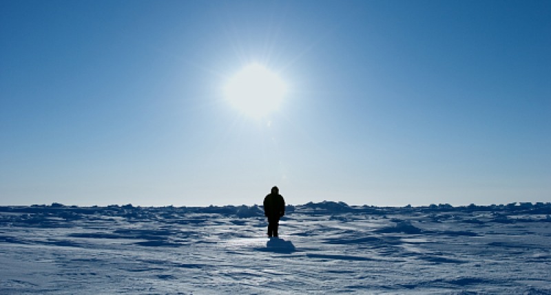 Photograph of a man standing on snow.