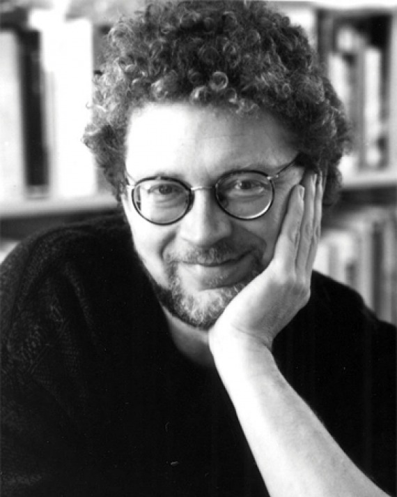 Black and white photograph of Sven Birkerts sitting in front of a bookshelf.