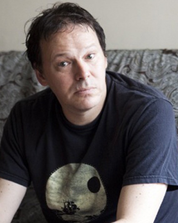 Color photograph of author David Graeber wearing a t-shirt.