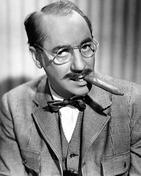 black and white photo of Groucho Marx wearing glasses and smoking a cigar from the side of his mouth