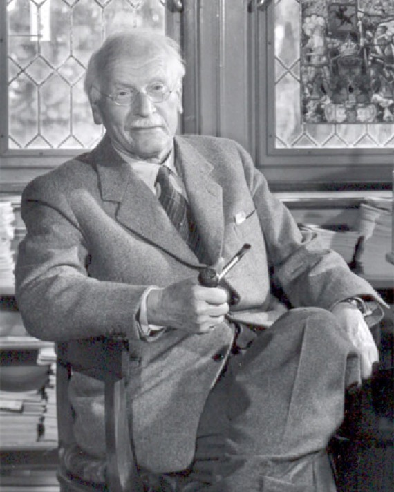 Black and white photograph of Swiss psychiatrist Carl Jung seated with legs crossed.