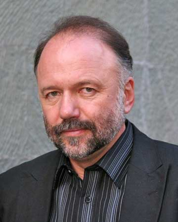 Man with a graying beard wearing a dark suit jacket