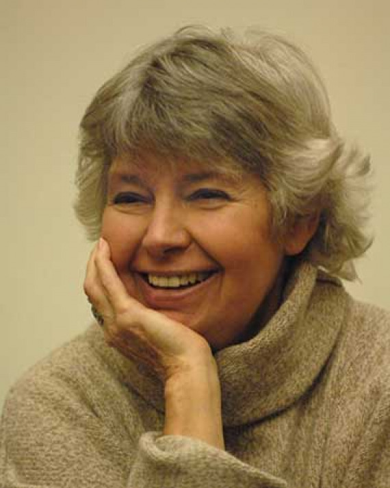 Photograph of a smiling gray-haired woman resting her chin in her right hand
