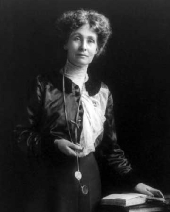 Emmeline Pankhurst Woman holding a lorgnette and standing next to a table, with her hand on an open book