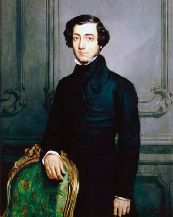 Portrait of Alexis de Tocqueville wearing a black suit and standing in front of a chair.