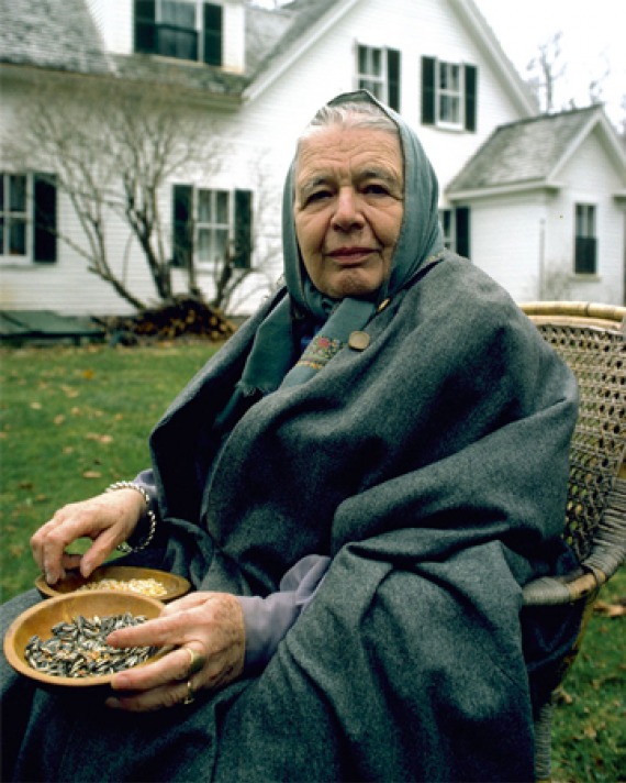 Photograph of Marguerite Yourcenar with a headscarf sitting in a chair outside.