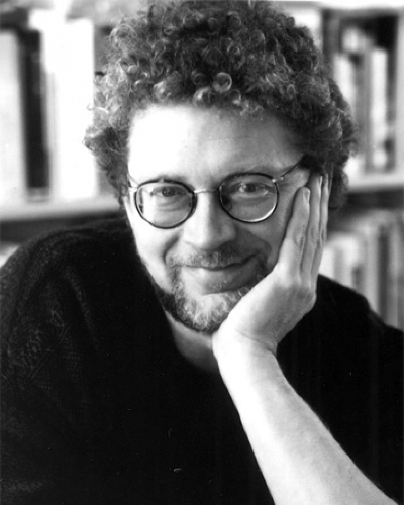 Black and white photograph of Sven Birkerts sitting in front of a bookshelf.