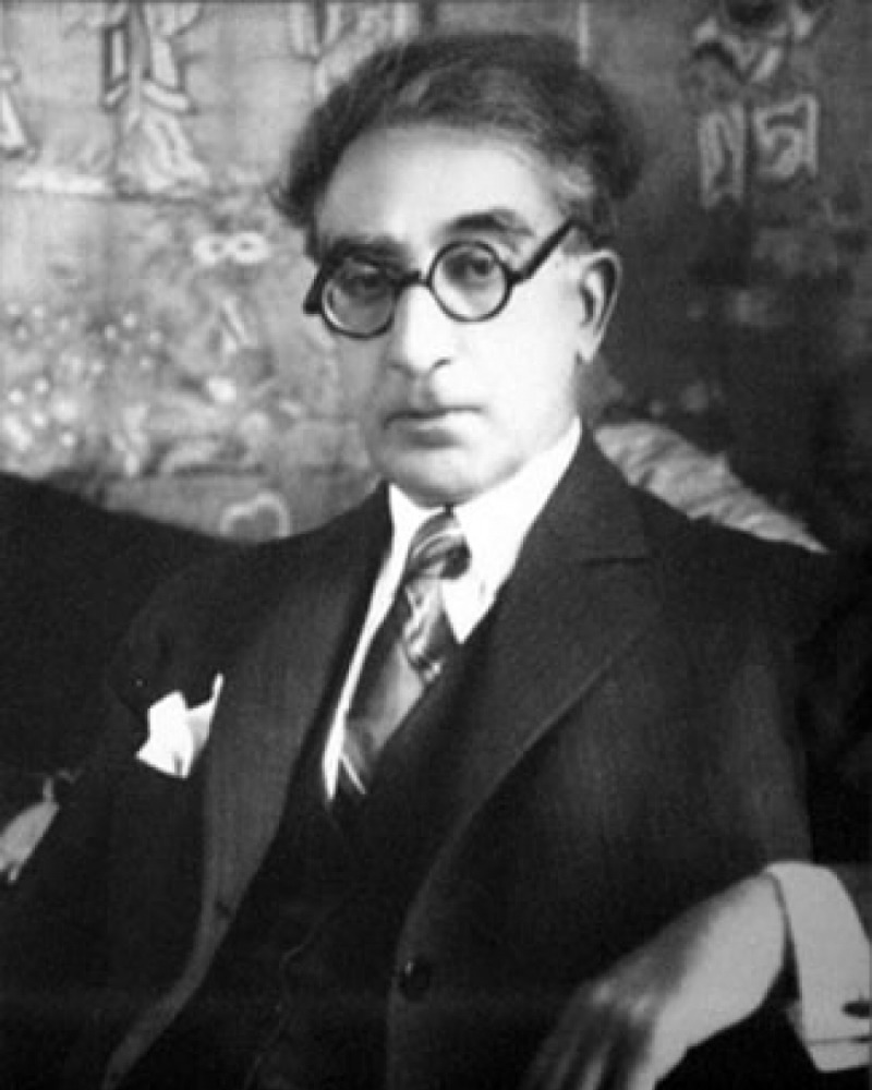 Black and white photograph of C. P. Cavafy wearing thick-rimmed black glasses. 