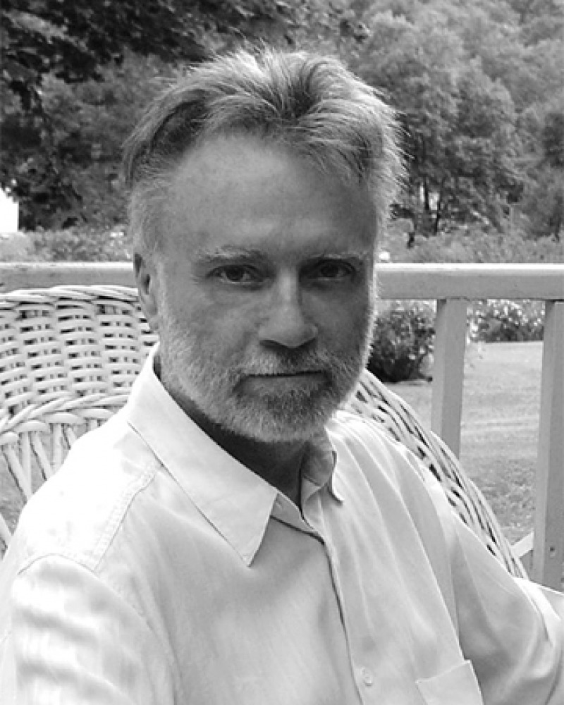 Black and white photograph of John Crowley sitting on a porch.