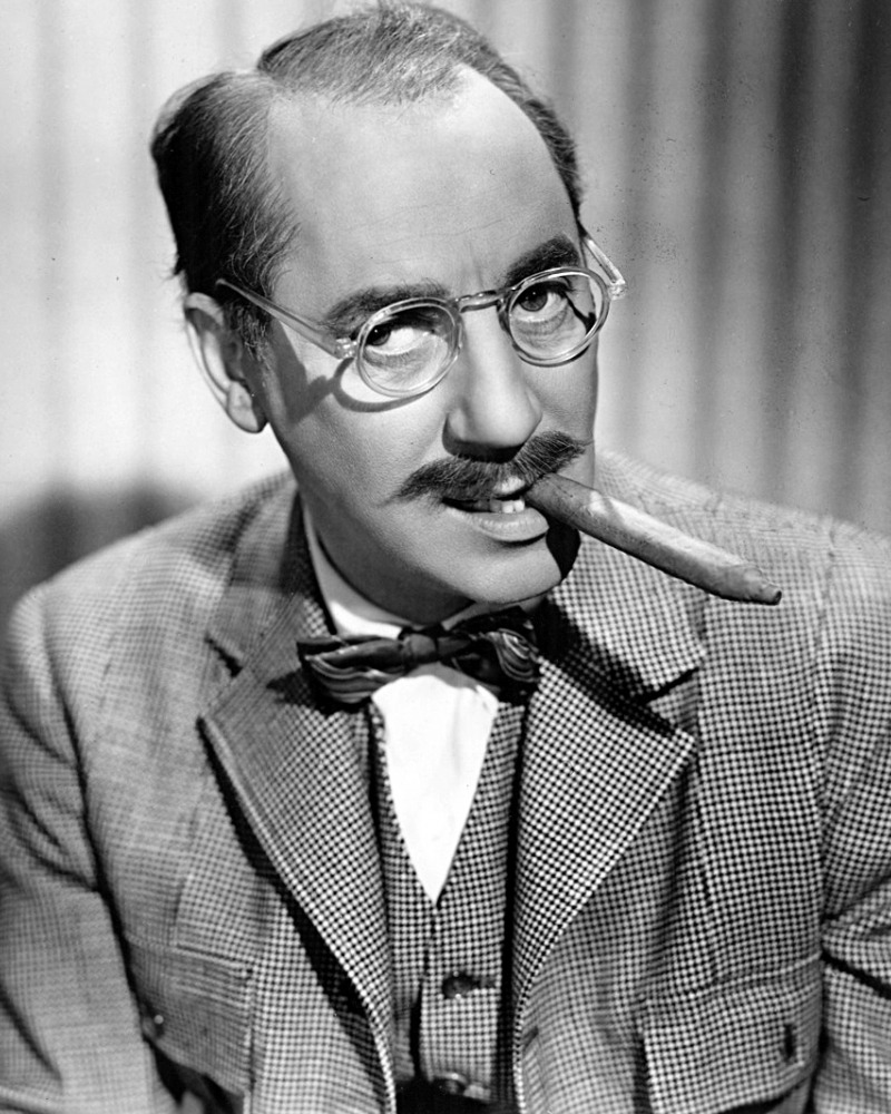 Groucho Marx black and white photo of Groucho Marx wearing glasses and smoking a cigar from the side of his mouth